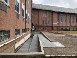 Newly constructed concrete accessibility ramp and walkway alongside a brick commercial building, showcasing site development improvements, safe pedestrian access, and concrete flatwork installation.